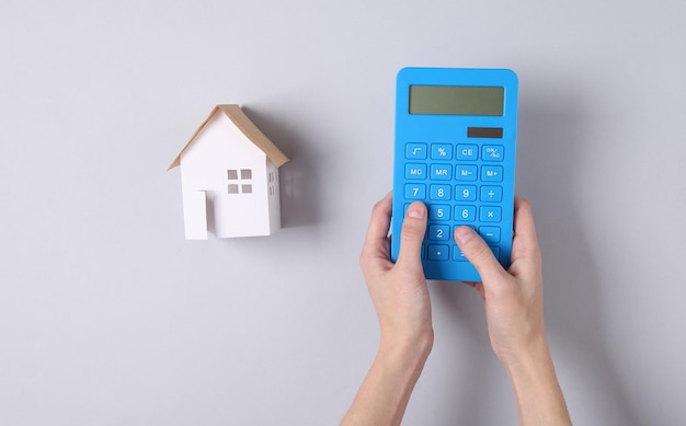 A close-up shot of a hand holding a calculator, with tax forms and a house key in the background, illustrating the calculation of tax deductions for homeowners.